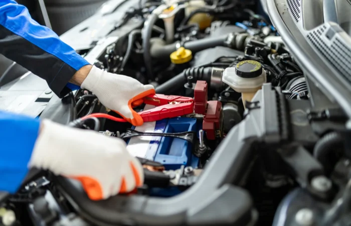 Professional roadside technician providing a car battery jump start service to a stranded vehicle in Waukegan, IL.